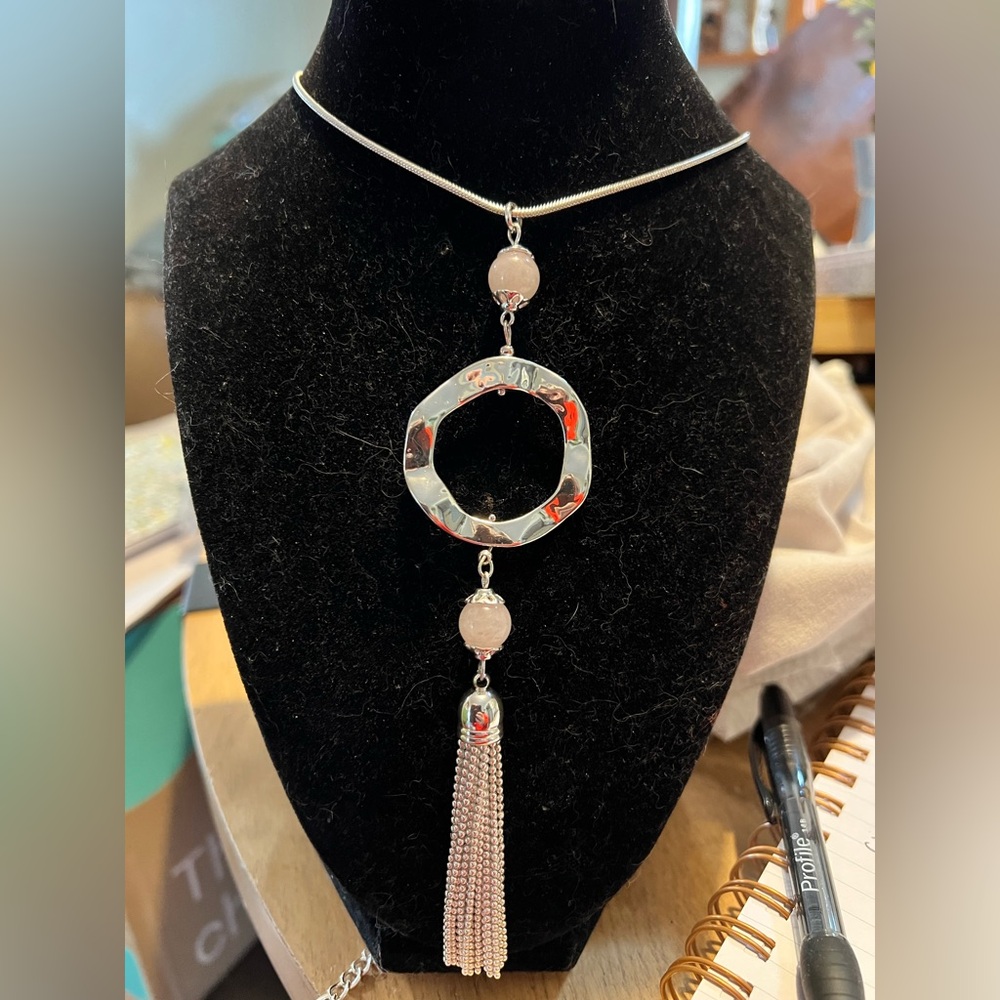 Silvertone statement necklace with pink beads, circular pendant and chain tassel